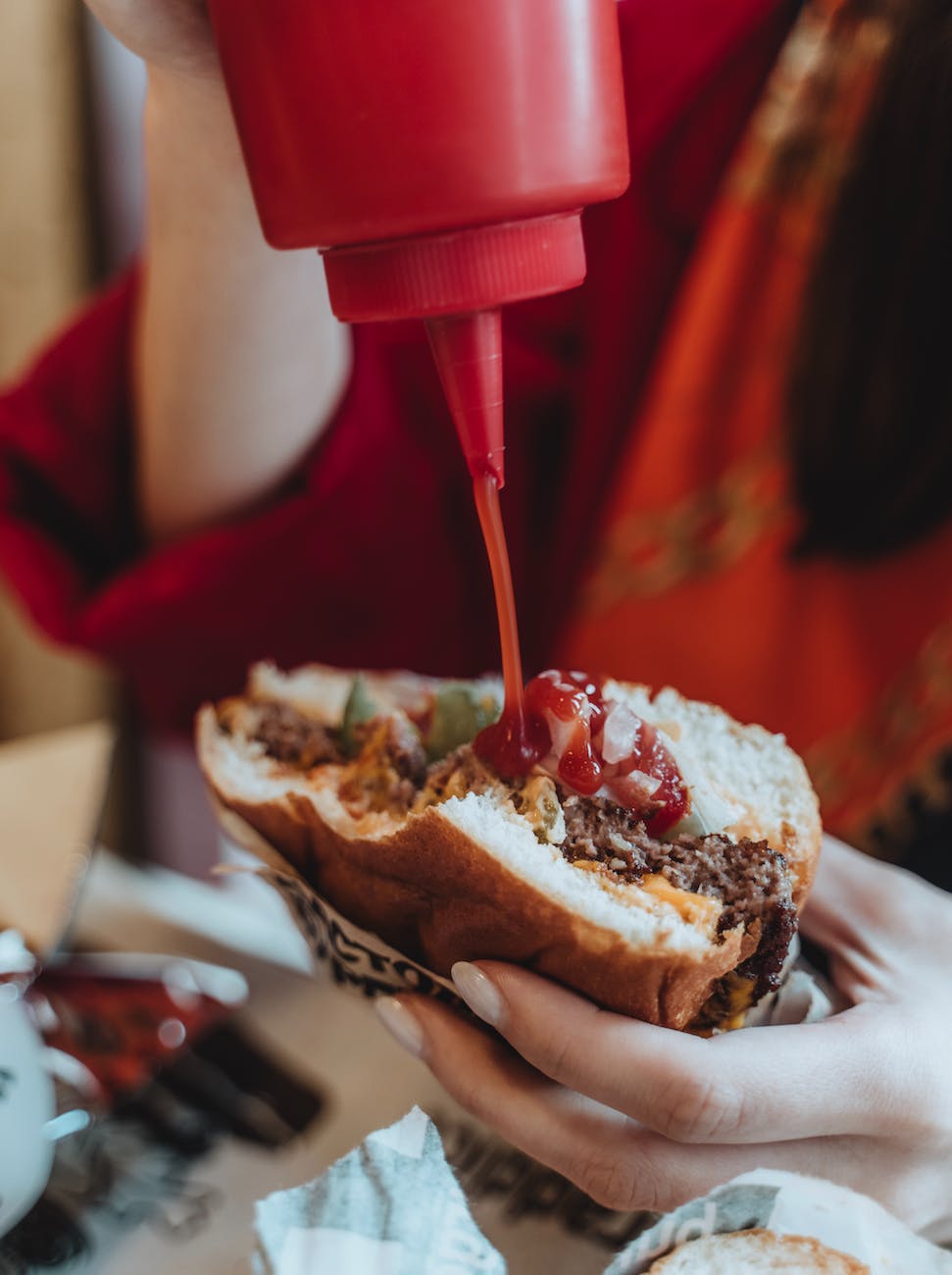 crop woman eating hamburger in cafe